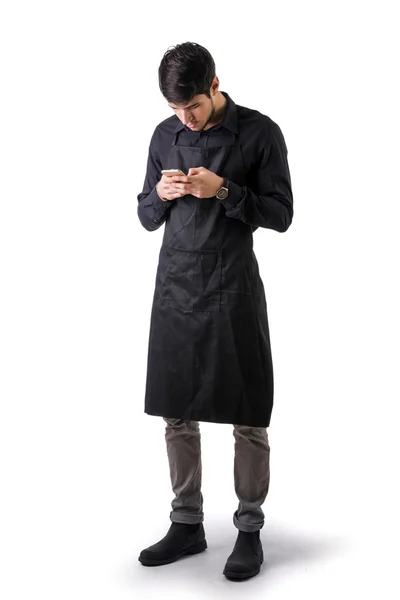 Jonge chef-kok of ober draagt zwarte schort geïsoleerd — Stockfoto