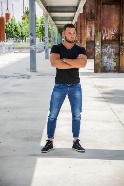 Handsome muscular man standing in city setting — Stock Photo, Image