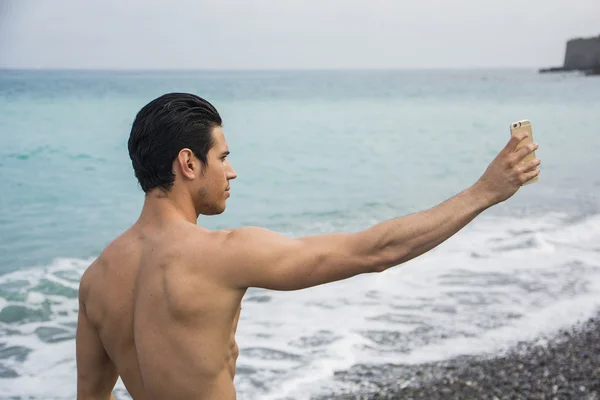 Jeune homme torse nu prenant des photos selfie à la plage — Photo