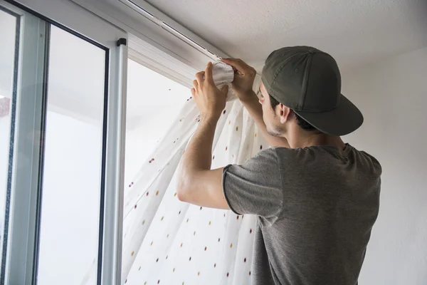 Joven, instalando cortinas en ventana —  Fotos de Stock