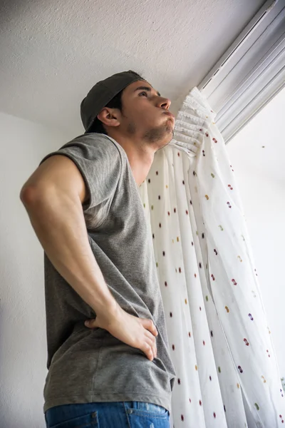 Jeune homme pose rideaux sur fenêtre — Photo