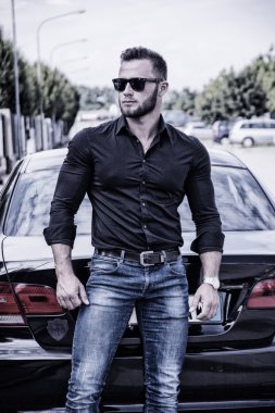 Handsome bearded man next to car in sunglasses