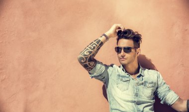 Turuncu duvara oturan yakışıklı adam