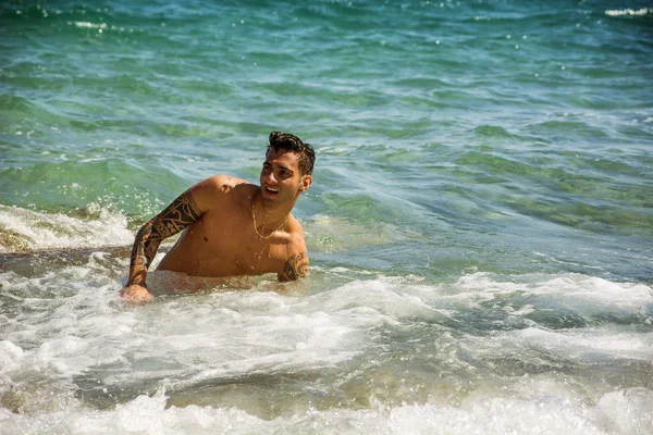 Young man standing in water by sea or ocean shore, — Stock Photo, Image