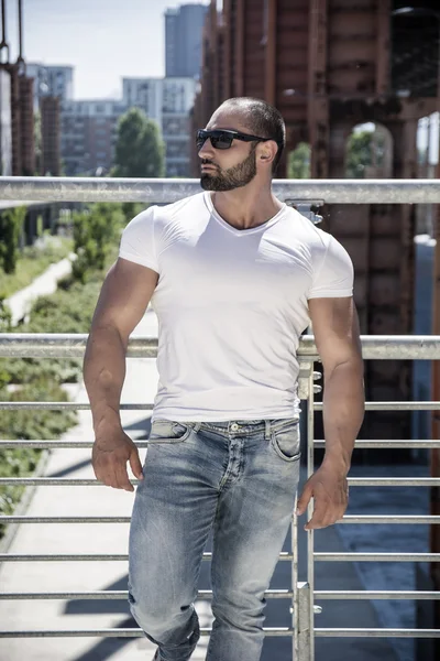 Handsome muscular man standing in city setting — Stock Photo, Image