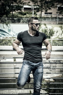 Yakışıklı kaslı adam şehir merkezinde duruyor.