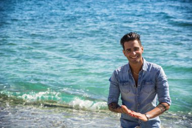 Genç adam güneşli yaz gününde plajda