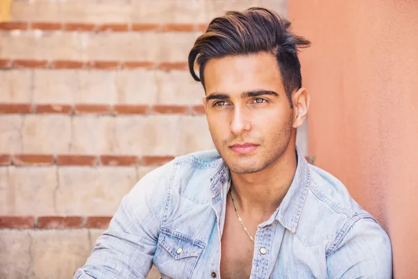 Handsome man sitting on stairs while looking at camera — Stock Photo, Image