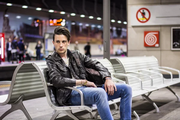 Young man traveling, next to train timetable in station — Fotografie, imagine de stoc