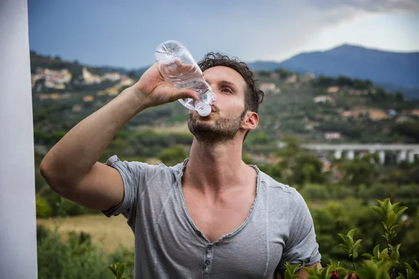 Handsome man drinking water from plastic bottle — Stock Photo, Image