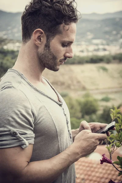 Fešák trendy muž pomocí mobilního telefonu na psaní textu — Stock fotografie