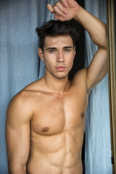 Sexy young man standing shirtless by curtains — Stock Photo, Image