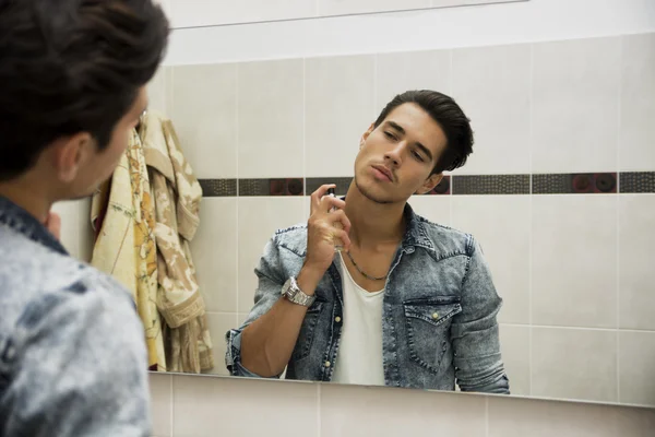 Jovem bonito no banheiro, pulverização de Colónia ou perfume — Fotografia de Stock