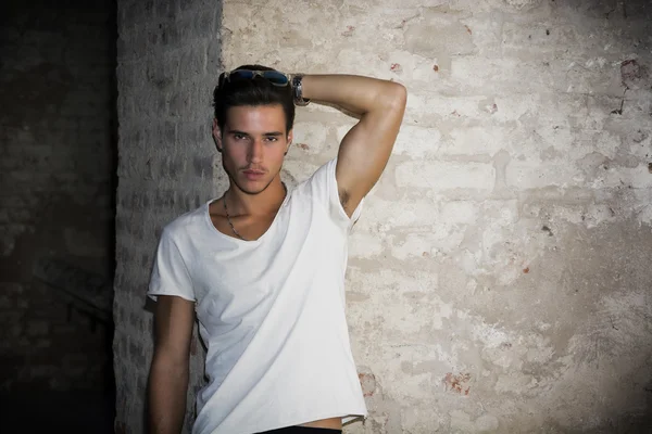 Handsome young man in old building against brick wall — Stock Photo, Image