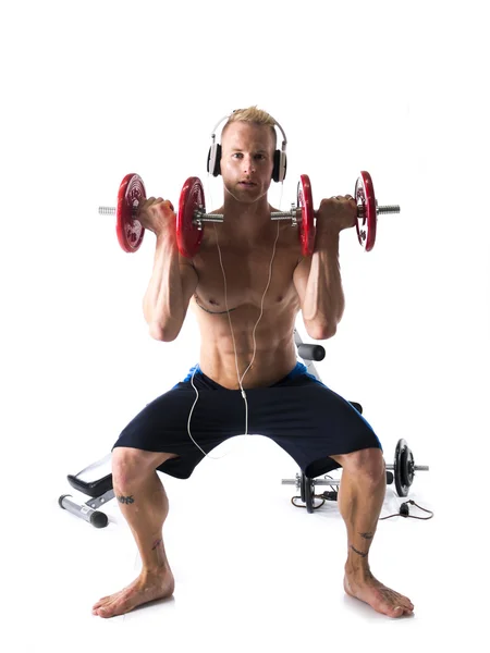 Hombre con los auriculares puestos, levantamiento de pesas en estudio —  Fotos de Stock