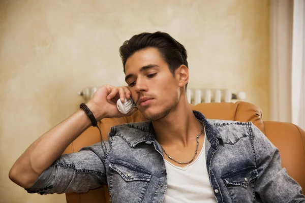 Beau jeune homme parlant au téléphone à la maison — Photo