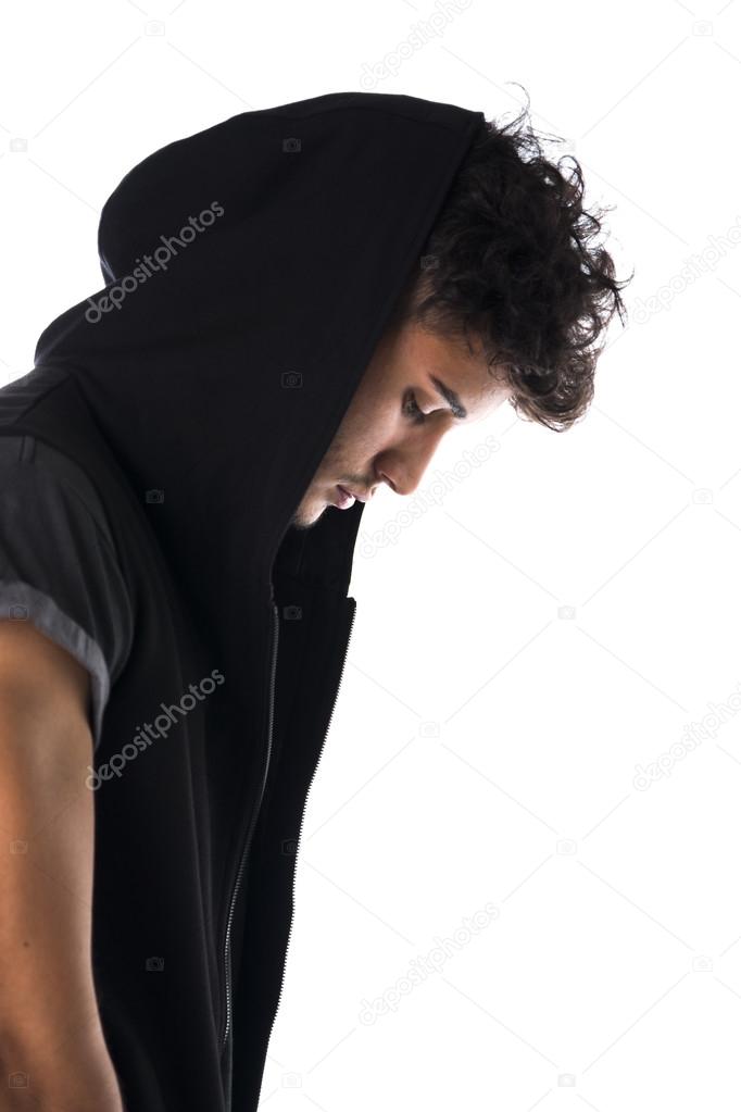 Portrait of handsome tough young man in dark hoodie isolated on white background, looking at camera