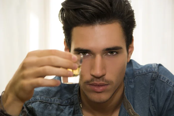 Seductive handsome young man sitting drinking — Stock Photo, Image