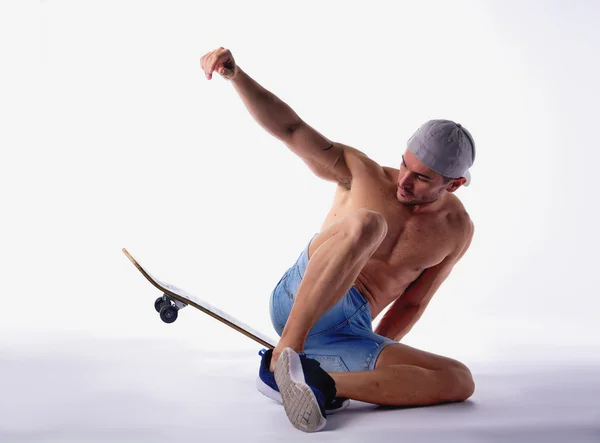 Nackter Oberkörper Mann sitzt auf Skateboard im studio — Stockfoto