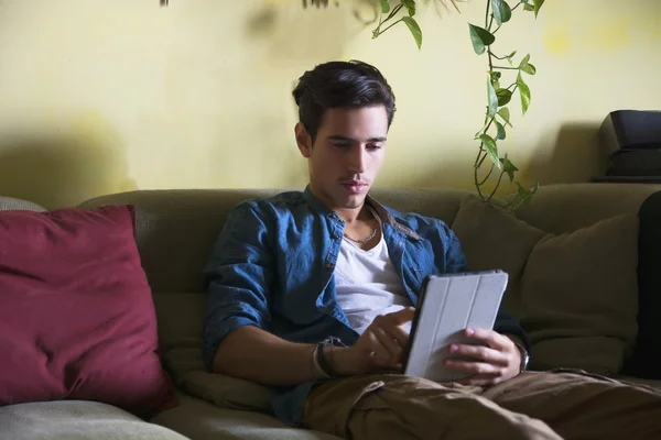 Jeune homme assis à l'aide d'une tablette — Photo