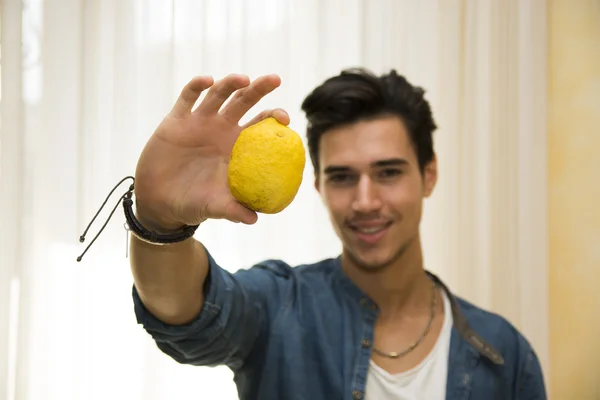 Giovane uomo che tiene un grande limone maturo delizioso — Foto Stock