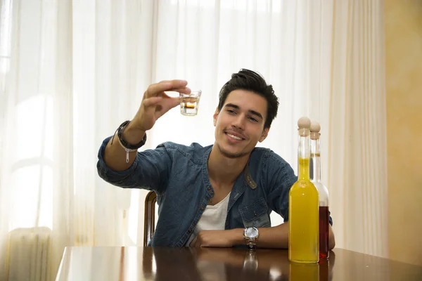 Young man sitting drinking alone at a table, making a toast — Stock Photo, Image
