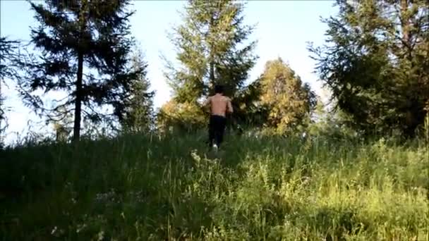 Junger Mann in Gefahr auf der Flucht einen Hügel hinauf und dann hinunter — Stockvideo