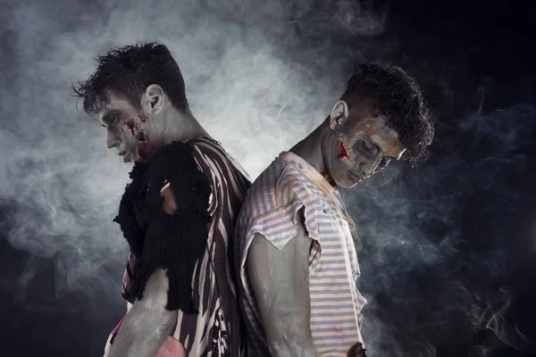 Dos zombies hombres espalda con espalda sobre fondo ahumado negro —  Fotos de Stock