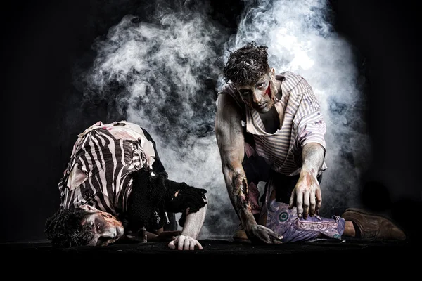 Dos zombies hombres arrastrándose sobre sus rodillas, sobre fondo ahumado negro —  Fotos de Stock