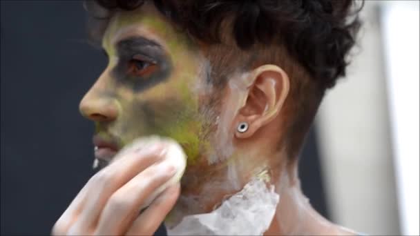 Молодой актёр или исполнитель наносит зомби-макияж на лицо — стоковое видео