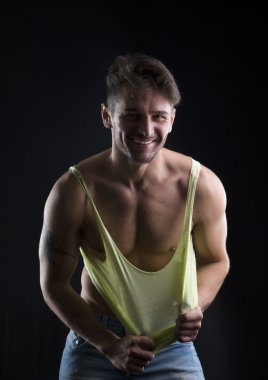 Tanktop yırtık kas gövde üzerinde aşağı çekerek genç atletik erkek
