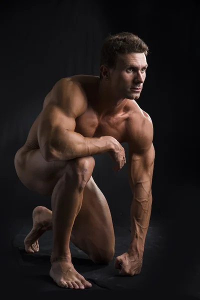 Полностью обнаженной молодой человек мышц, стоя на коленях на черном — стоковое фото