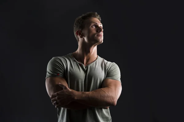 Handsome muscular fit young man on dark background looking up — Stock Photo, Image