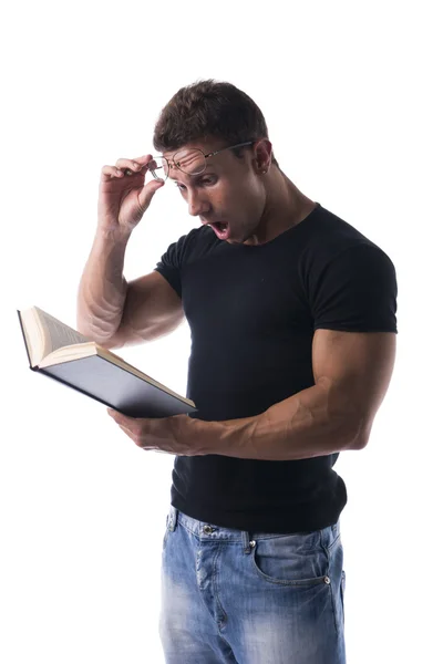 感到惊讶或震惊的英俊性感肌肉男看书 — 图库照片