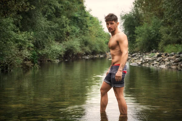 Przystojny młody mężczyzna mięśni stojący w stawie woda nago — Zdjęcie stockowe