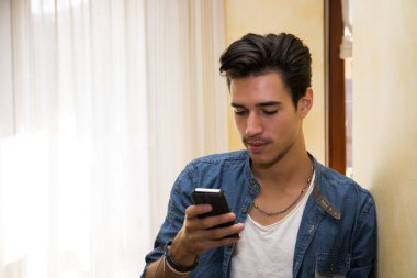 Evde oturma odası yazma veya okuma cep telefonundan, kapalı çekici genç adam vurdu