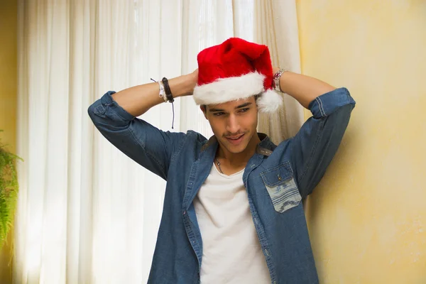 Casual jovem celebrando o Natal em seu chapéu de Papai Noel vermelho — Fotografia de Stock