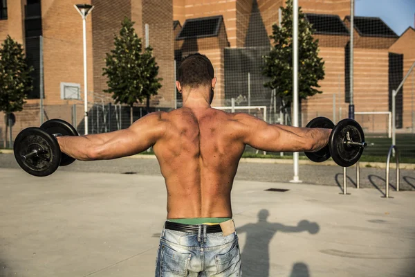 屋外の重みを持ち上げて魅力的な筋肉の塊男裏 — ストック写真