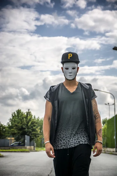 Genç adam giyen beyaz tüyler ürpertici maske şehir sokak açık
