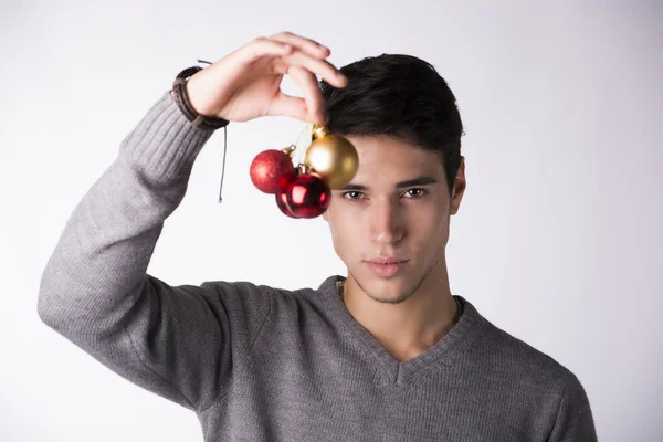 Atractivo joven sosteniendo bolas de árbol de Navidad —  Fotos de Stock