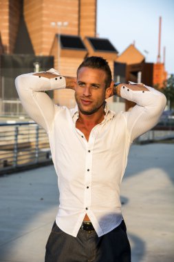 Yakışıklı kaslı sarışın adam ayakta şehir ortamda gülümseyen