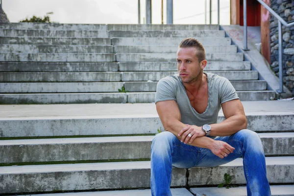 Bel homme blond musclé assis sur les marches d'escalier — Photo