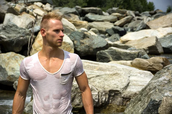 Guapo musculoso joven de pie, vistiendo camiseta blanca mojada —  Fotos de Stock