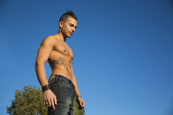 Handsome fit athletic shirtless young man against blue sky — Stock Photo, Image