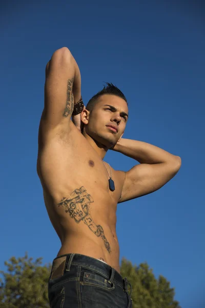 Handsome fit athletic shirtless young man against blue sky — Stock Photo, Image