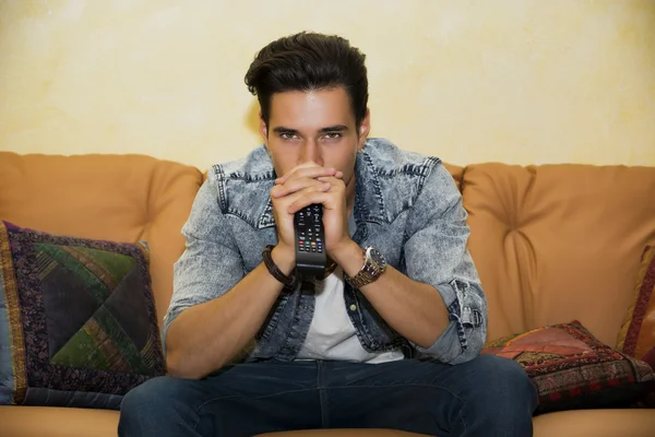 Young man sitting watching television changing the channel — Stock Photo, Image