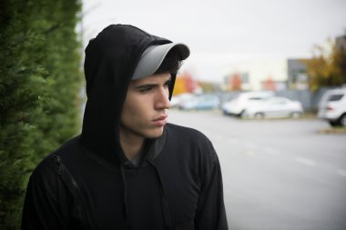 Şehirde hoodie ve beyzbol kap ile çekici genç adam