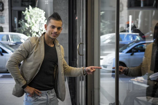 Aantrekkelijke jonge man wijzende vinger op etalage — Stockfoto