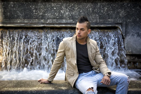 Séduisante jeune homme dans un milieu urbain, assis — Photo