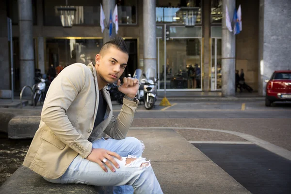 Attractive young man in urban setting, sitting — Stock Photo, Image